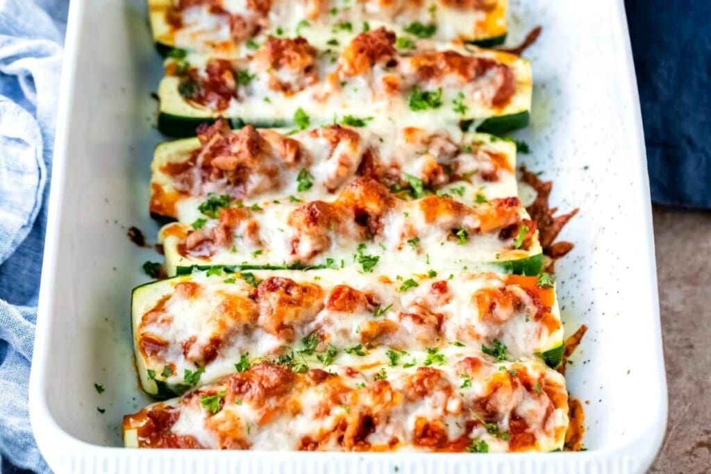 Close-up of zucchini boats in a white rectangular baking dish.