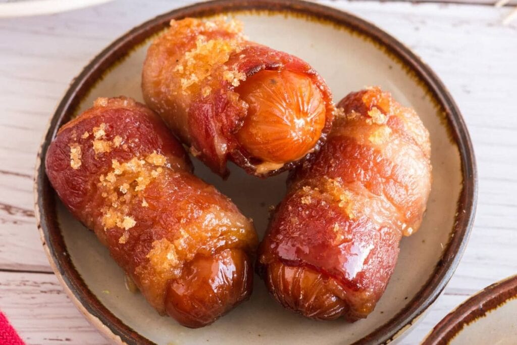 Bacon wrapped little smokies on a plate.