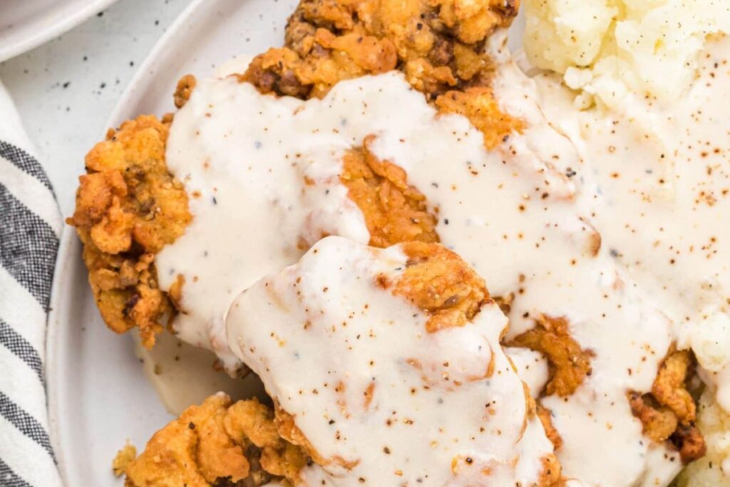 Close up shot of chicken fried steak with white gravy.