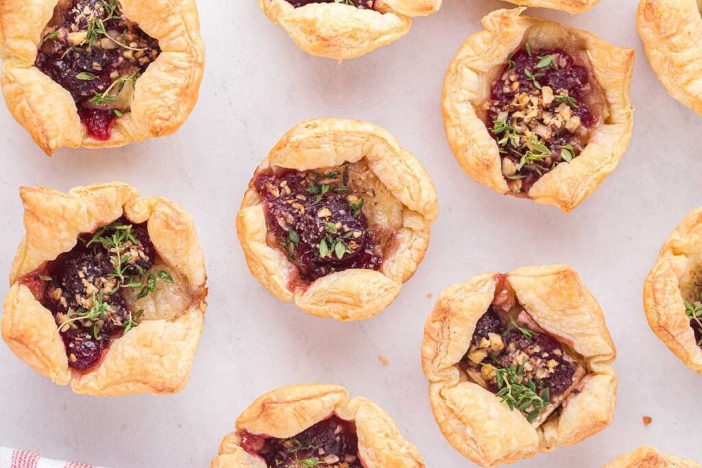 Cranberry brie bites on a white surface.