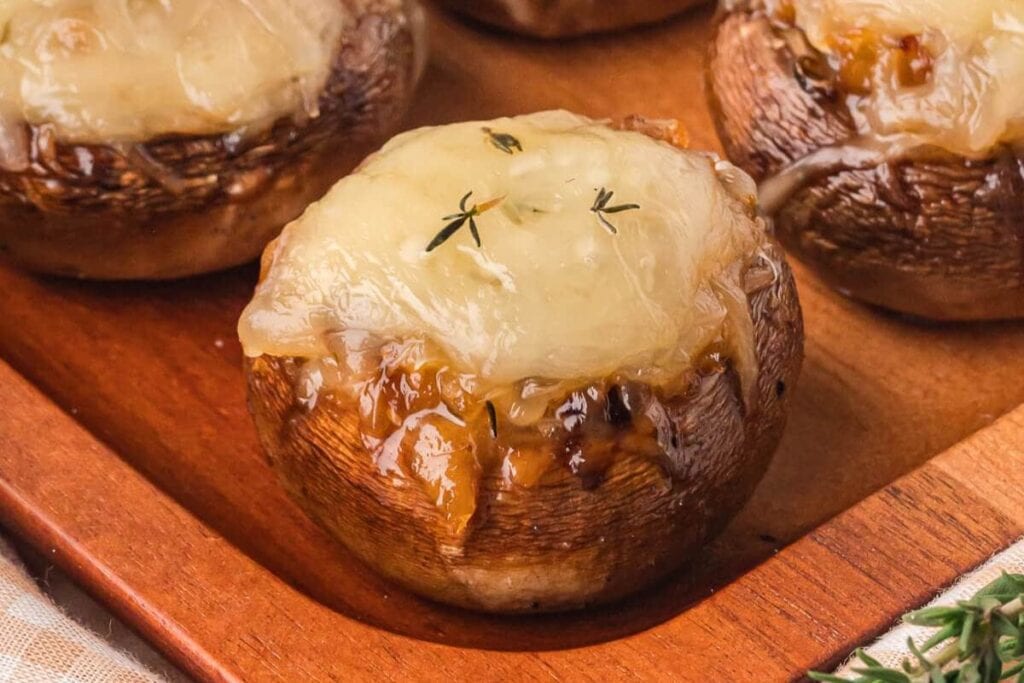 Onion stuffed mushroom on a wooden board.
