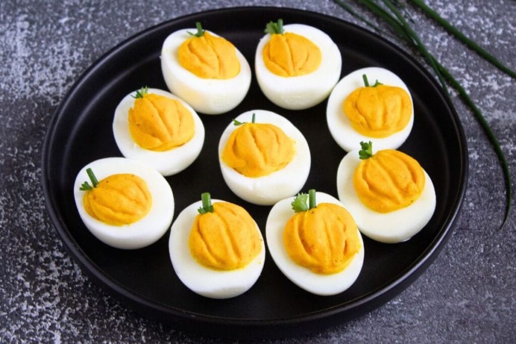 Pumpkin deviled eggs on a plate.