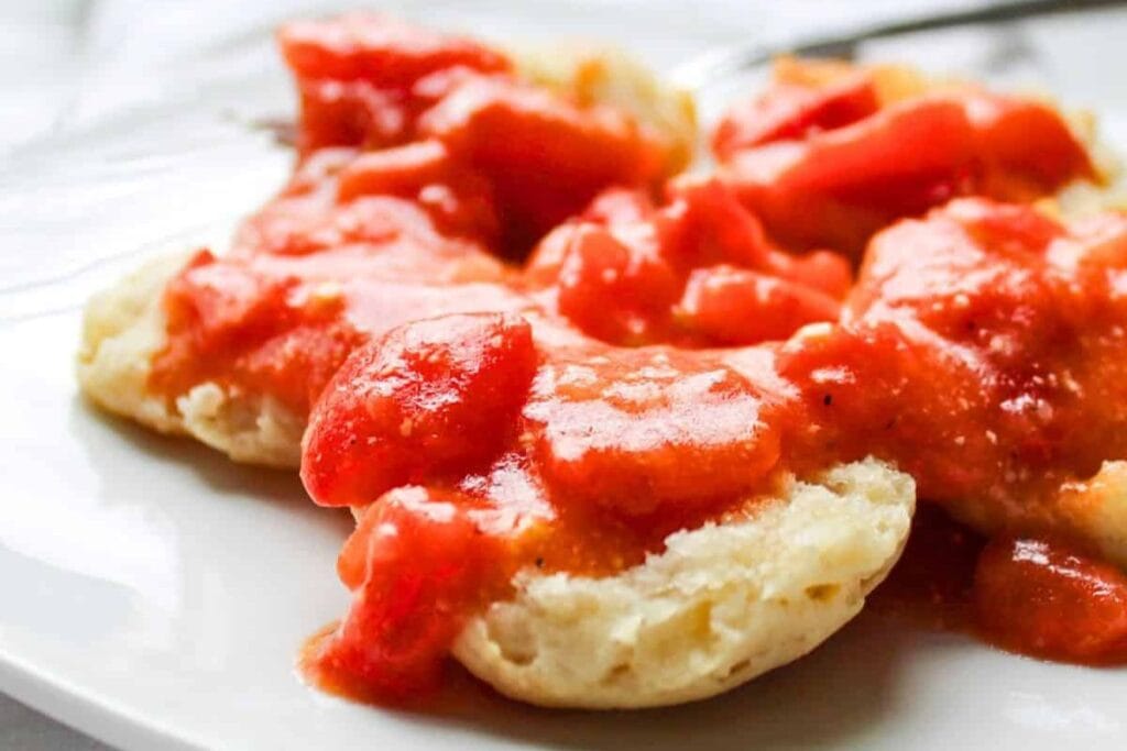 Close up shot of a biscuit with tomato gravy.