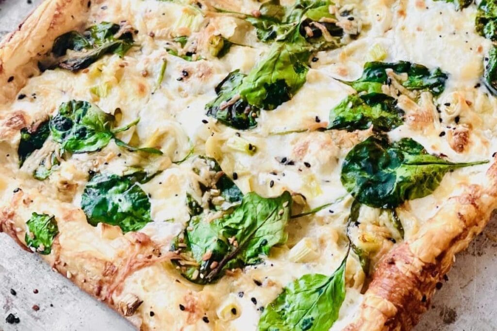 Close up shot of spinach alfredo pizza.