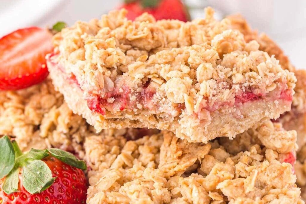 A close up shot of oatmeal bars with strawberries.