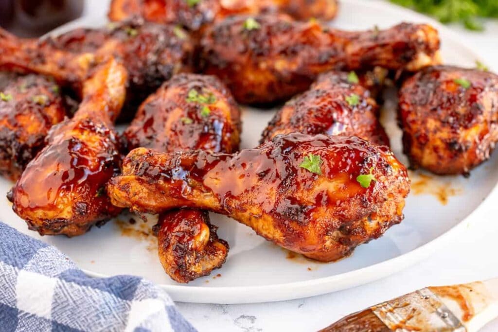 BBQ chicken drumsticks cooked in an air fryer, served on a white plate.