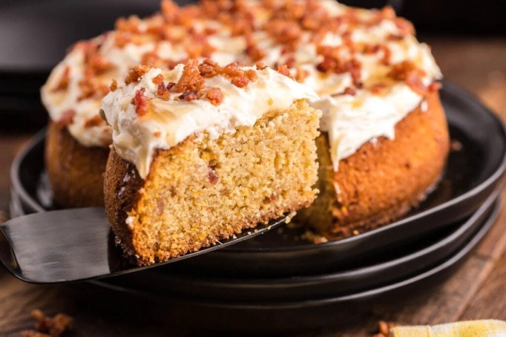 Slice of frosted cornbread cake lifted with a spatula.