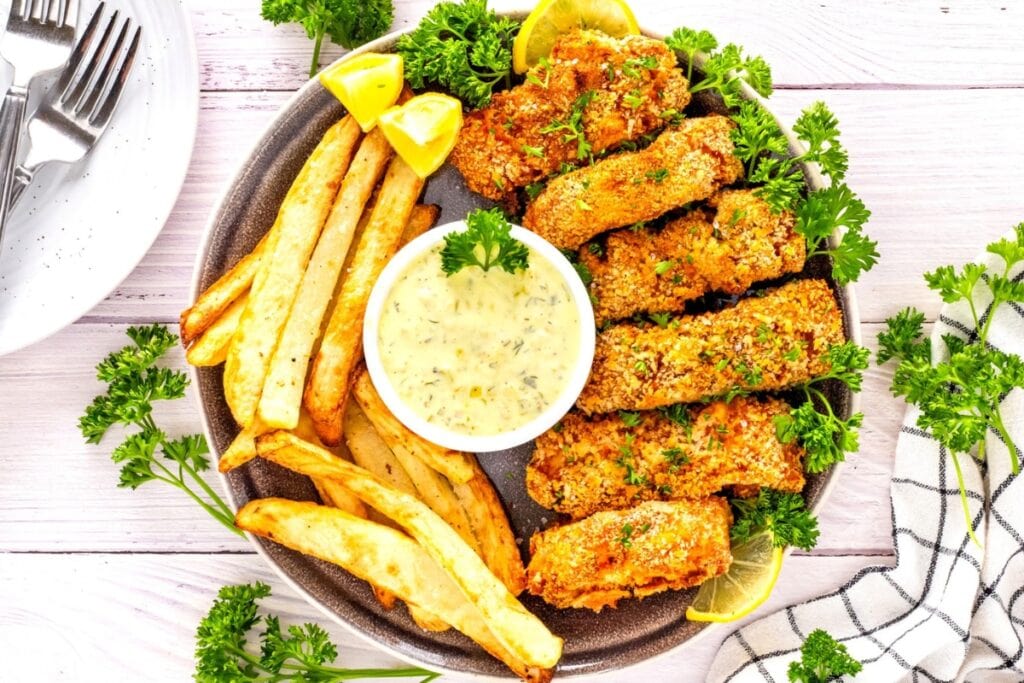 Crispy fish and chips with lemon, dipping sauce, and parsley.