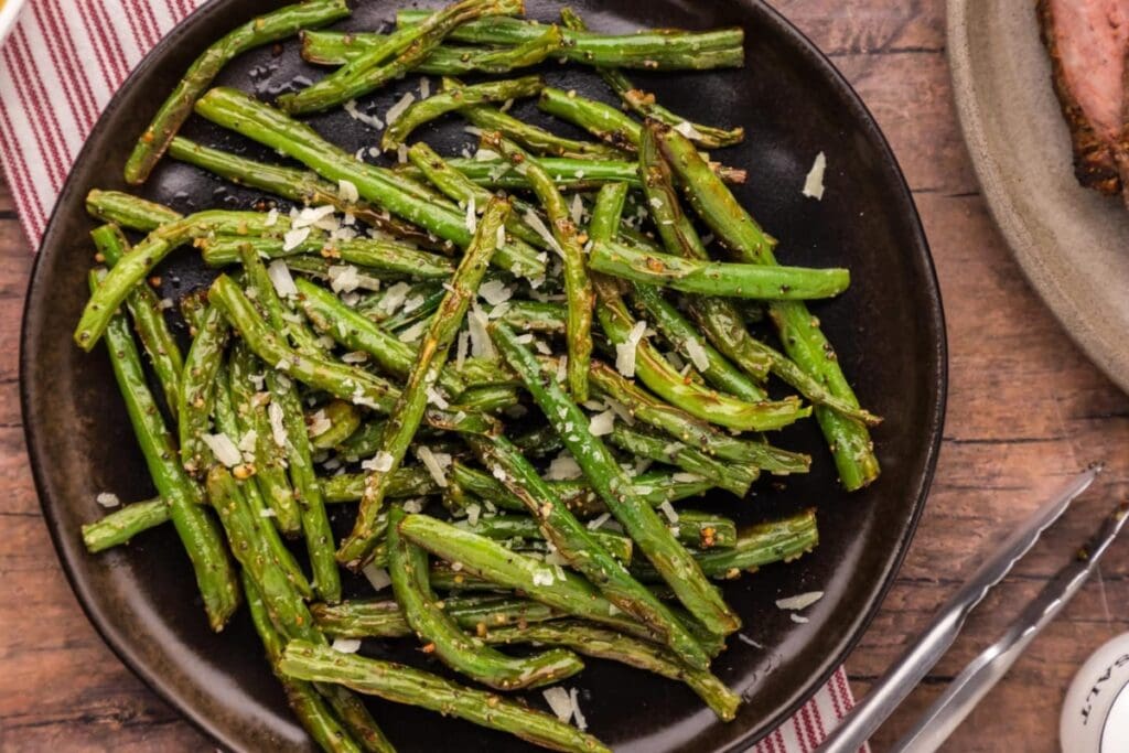 Air fryer green beans on a black plate.