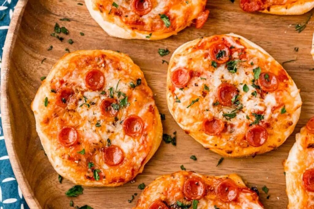 Mini pizzas on a wooden plate.