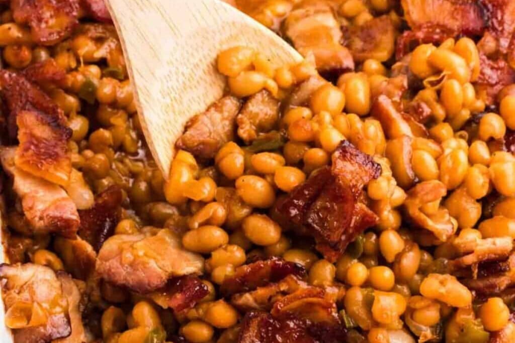 Baked beans scooped with a wooden spoon.