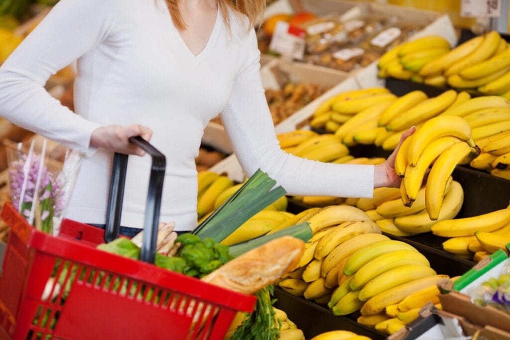 Woman holding a bunch of bananas in a grocery store.