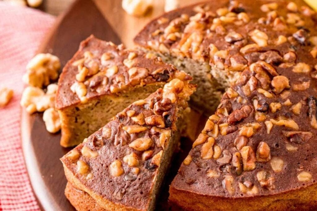 Whole banana bread with slices on a wooden board.