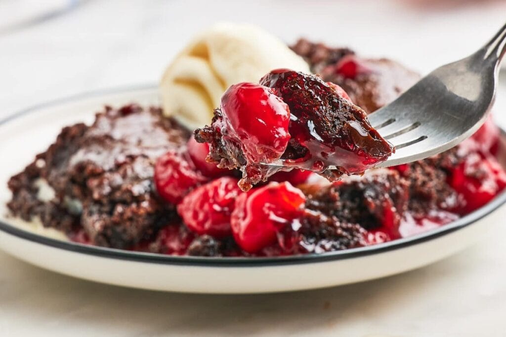 Fork scooping Black Forest Dump Cake from a plate.