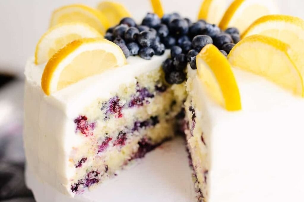 Blueberry lemon layer cake with one slice out.