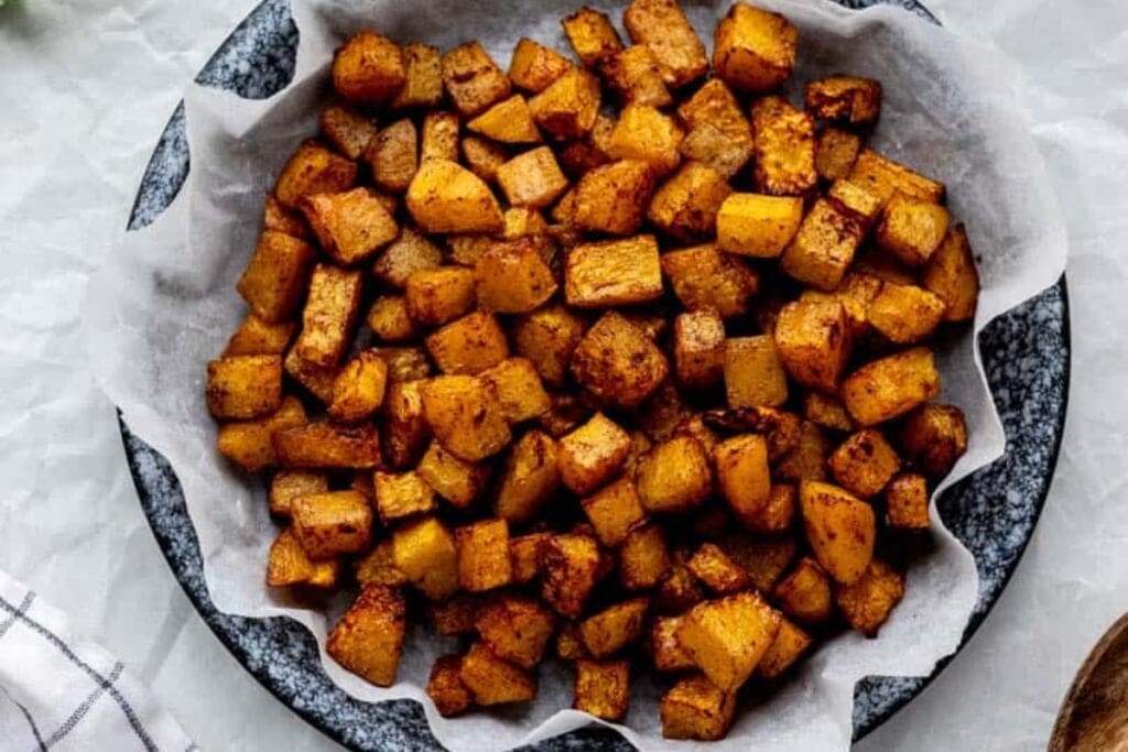 Butternut squash on a plate lined with parchment paper.