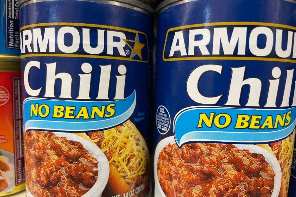Canned chili on a shelf.
