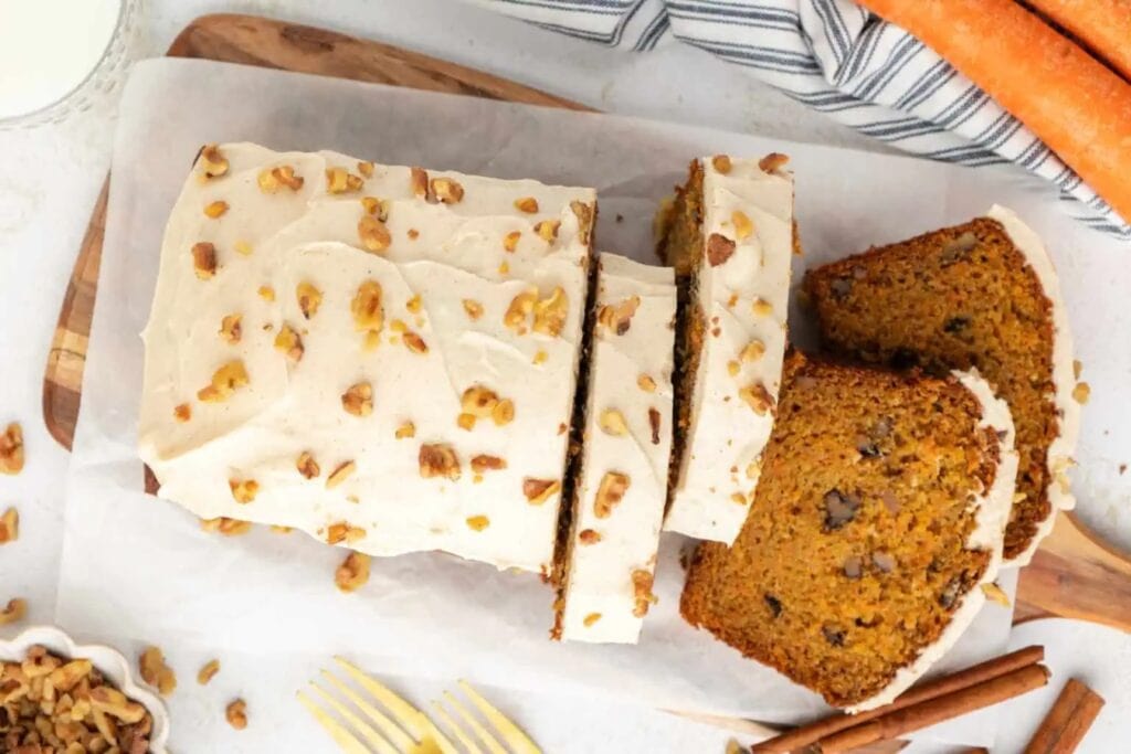 Carrot loaf cake on parchment paper over a wooden board.