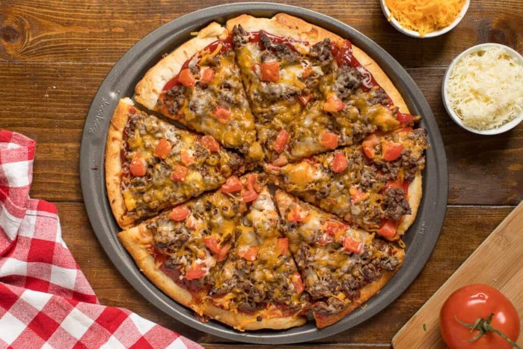 Cheeseburger pizza on a pizza pan.
