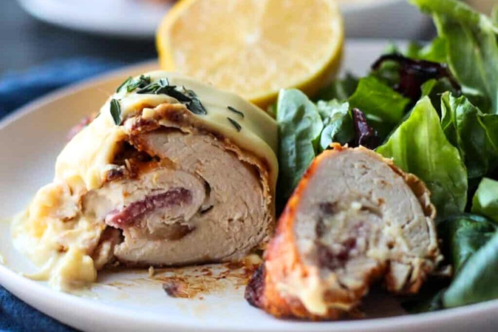 Chicken Cordon Bleu stuffed with ham and cheese, served with vegetables and a lemon slice.