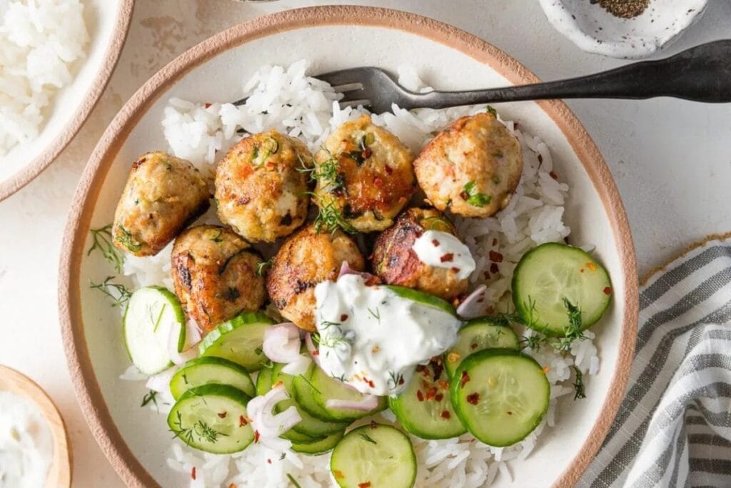 Chicken zucchini meatballs with rice on a white plate.