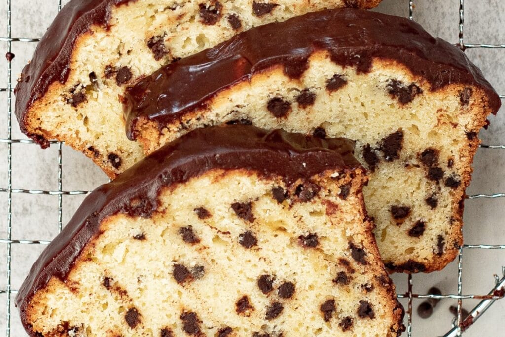 Three slices of chocolate chip loaf cake on a cooling rack.
