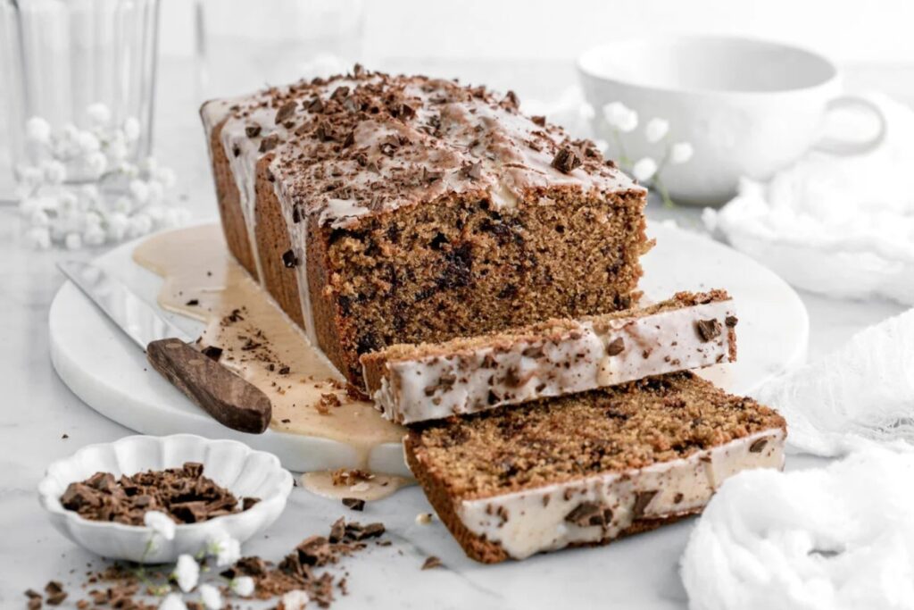 Chocolate chunk espresso loaf cake with glaze and two slices cut.