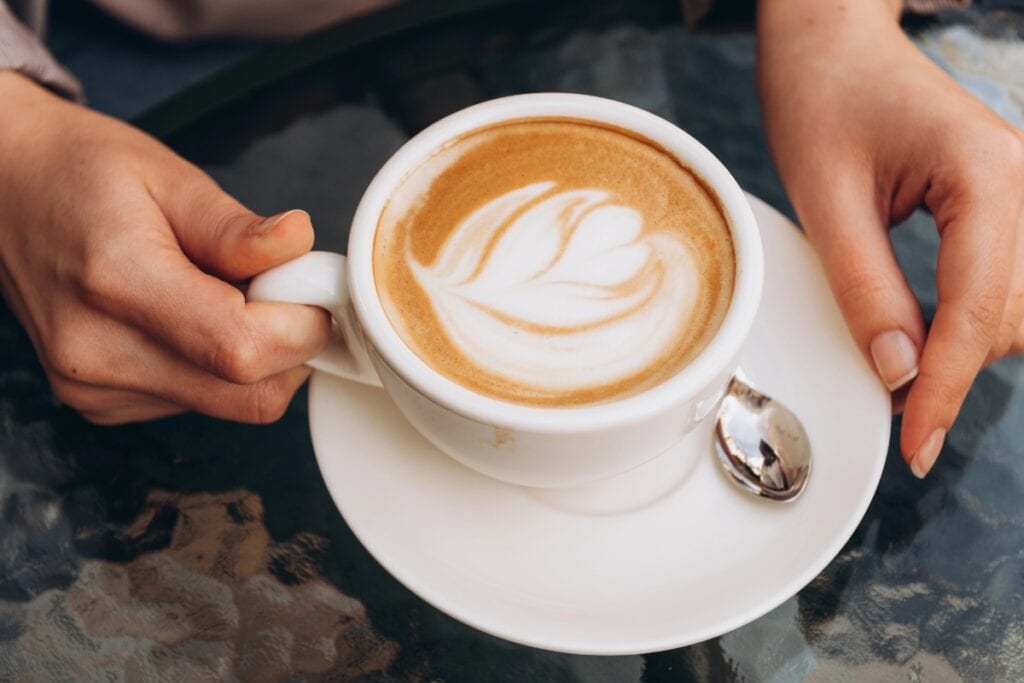 Woman holding a latte coffee drink.