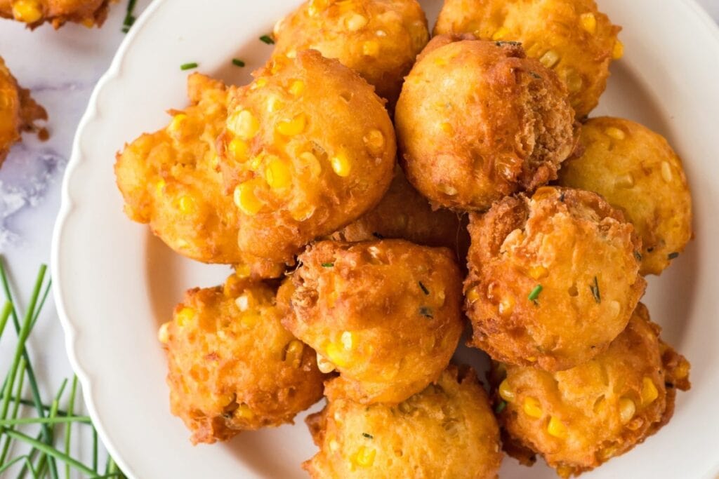 Golden corn fritters served on a white plate.