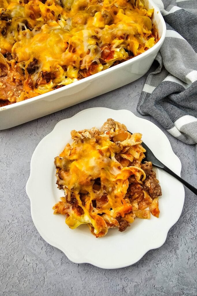 Creamy beef noodle casserole in a white rectangular baking dish and on a white plate.