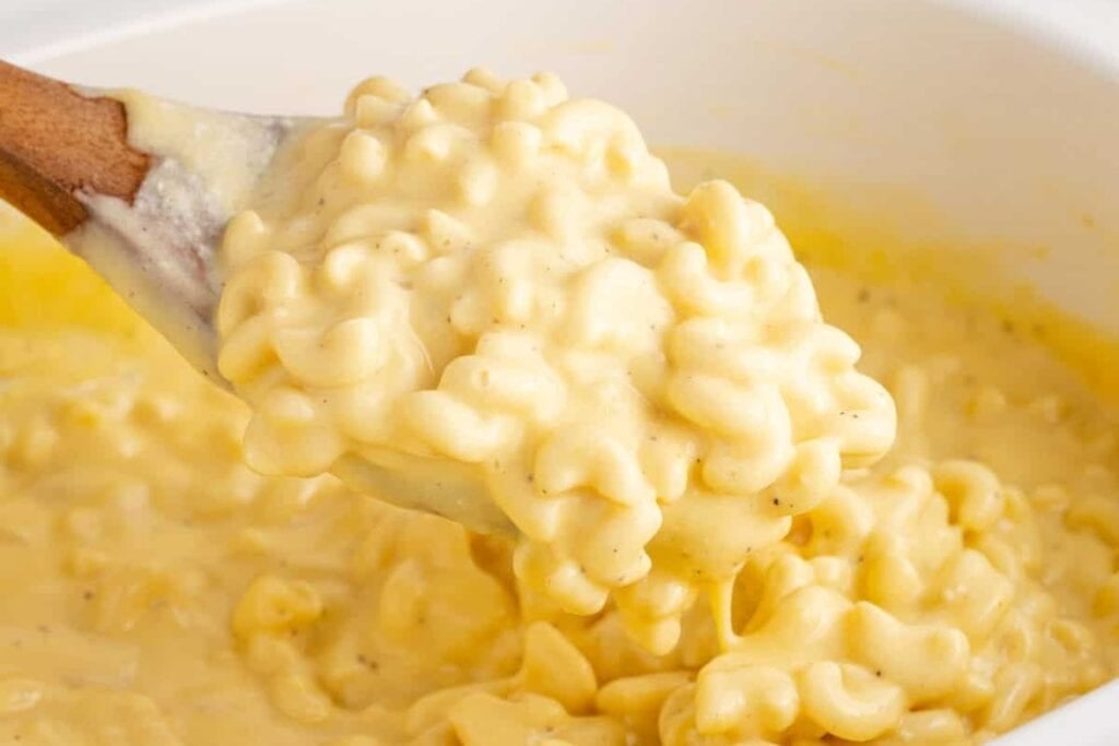 Crockpot mac and cheese scooped with a wooden serving spoon.