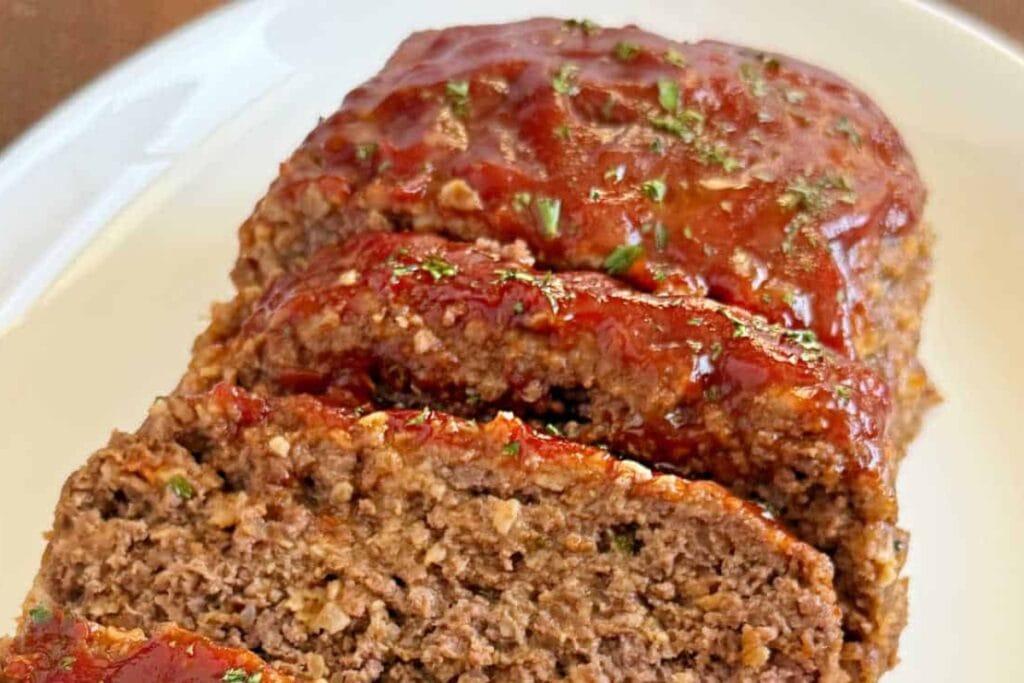 Sliced crockpot meatloaf on a rectangular white plate.