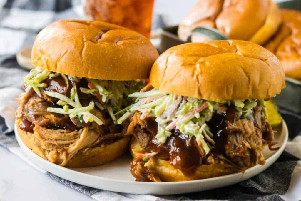Two crockpot root beer pulled pork sandwiches on a plate.