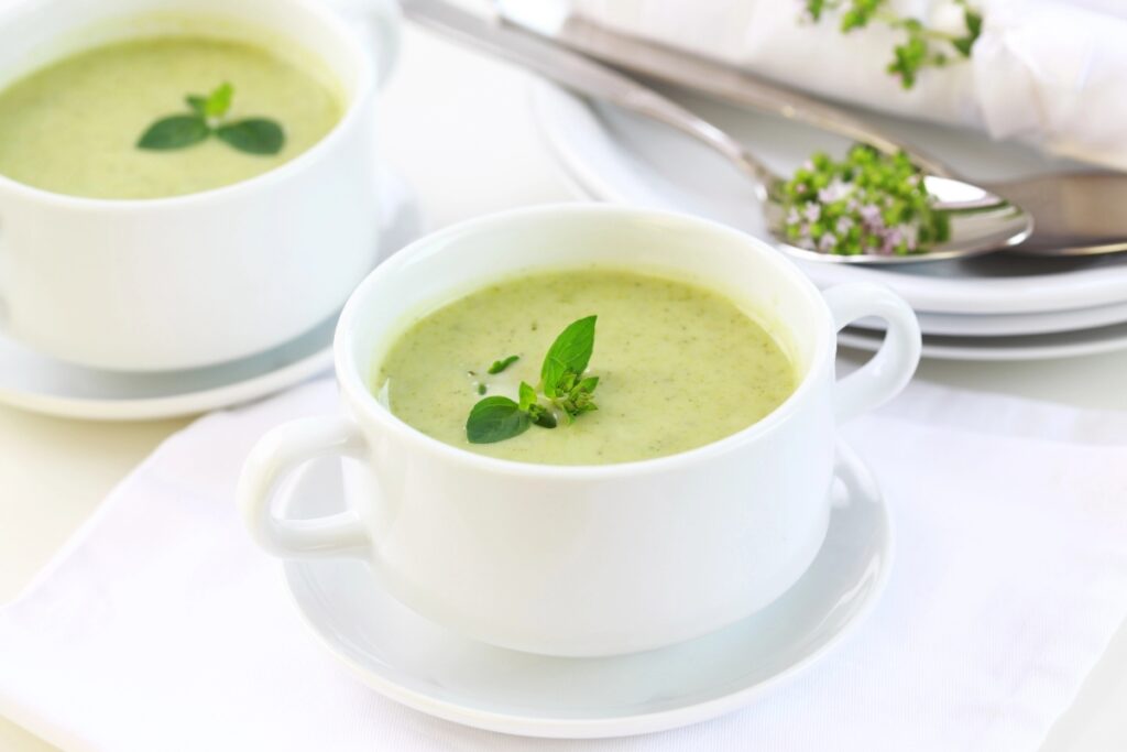 A cup of hot soup garnished with fresh mint leaves.