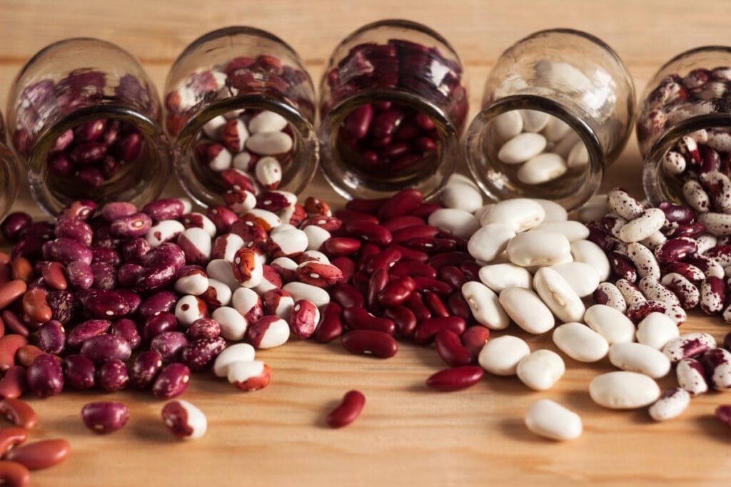 Multi-colored beans are poured out of jars on the table.