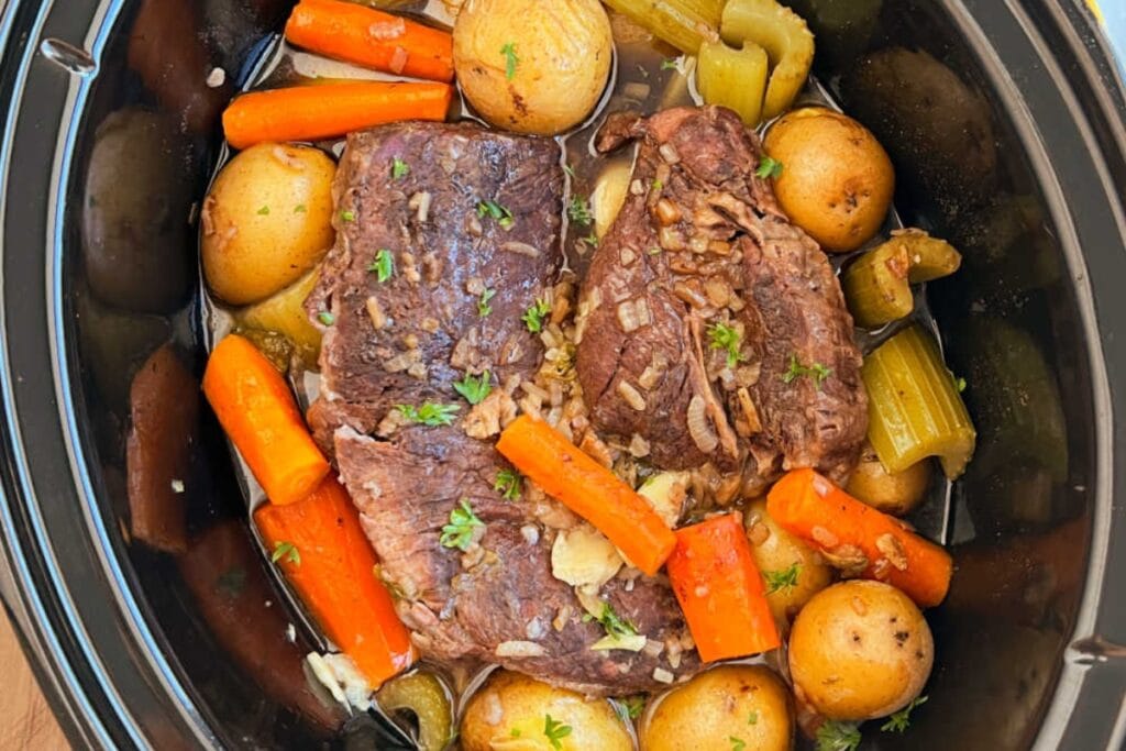 Crockpot pot roast with carrots, potatoes, and celery.