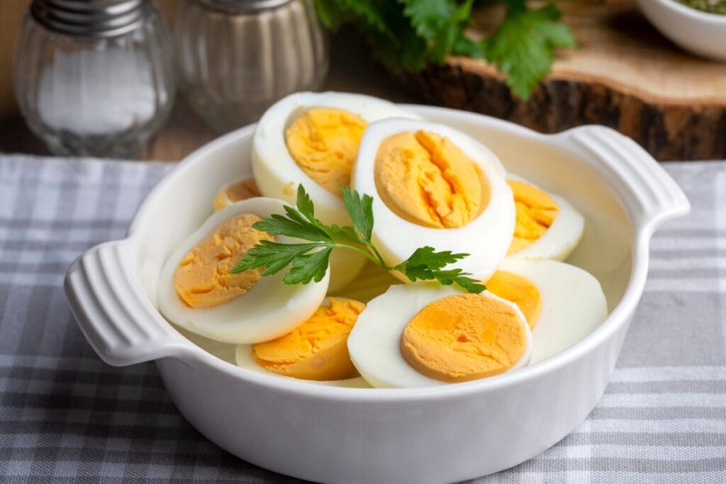 Sliced eggs in a white handled bowl.