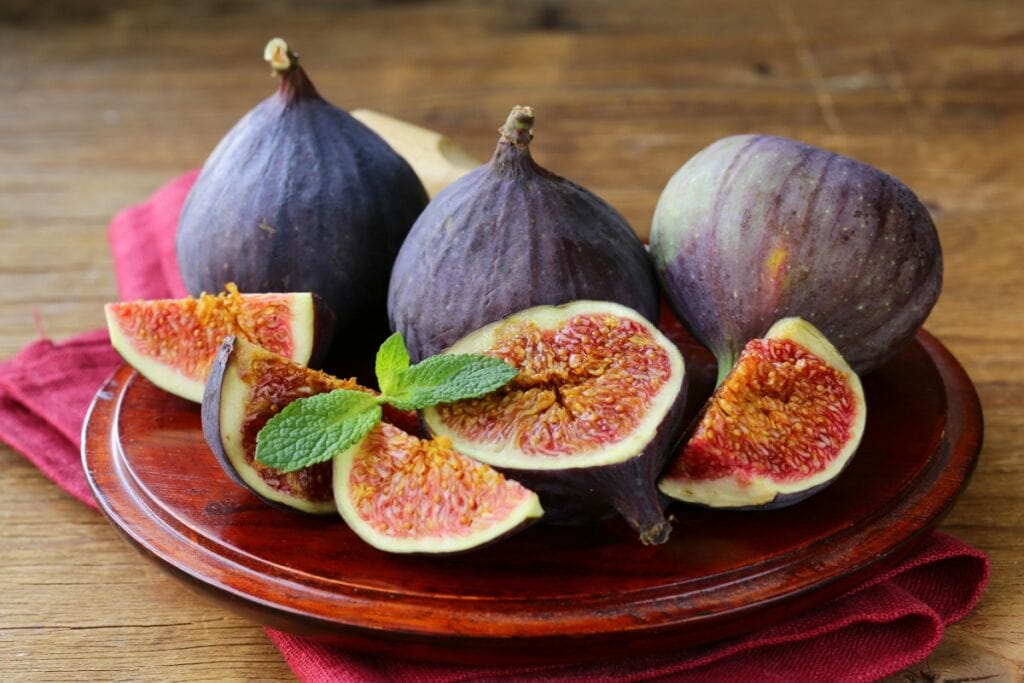 Fresh figs on a round wooden plate.