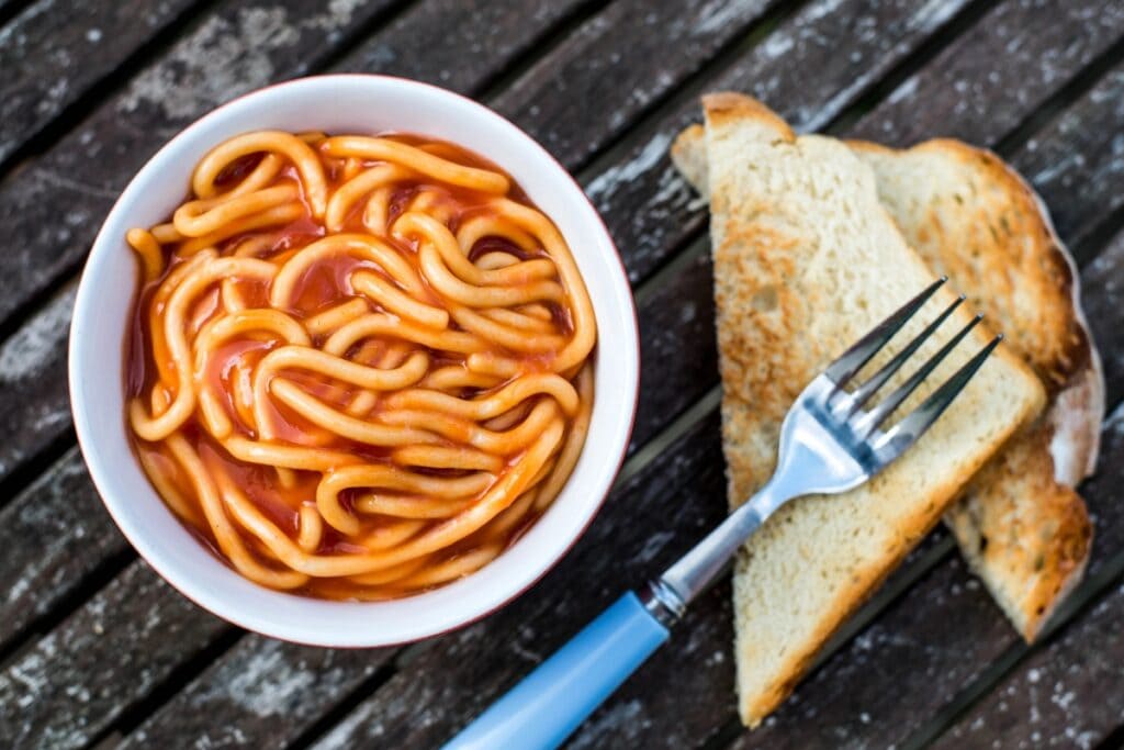 Franco American spaghetti in a white bowl with toast and fork.