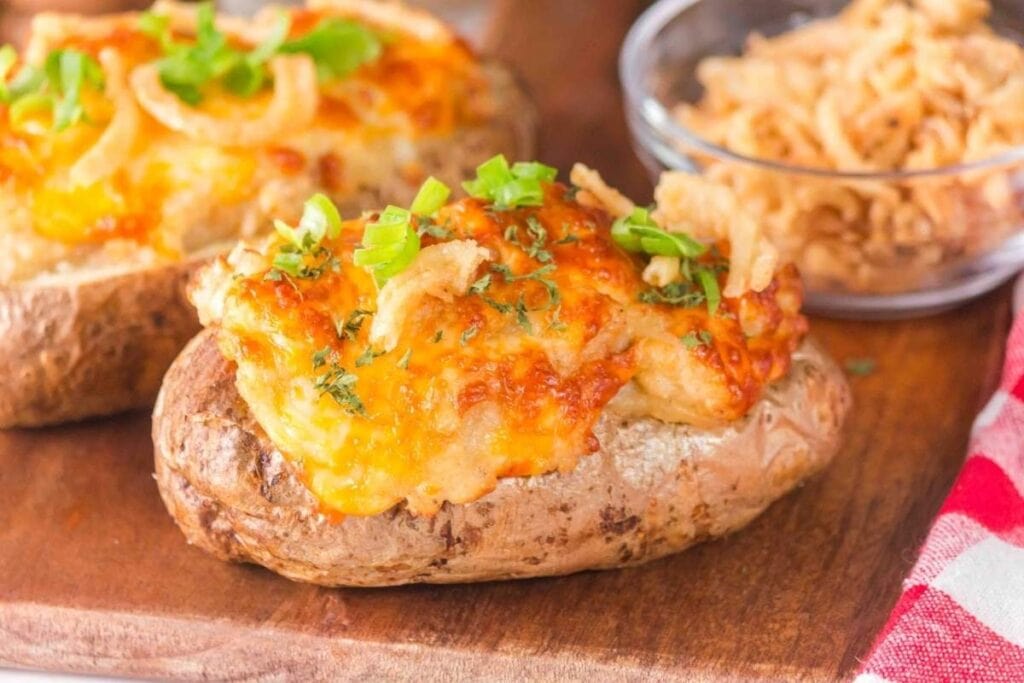 French onion baked potatoes on a wooden board.