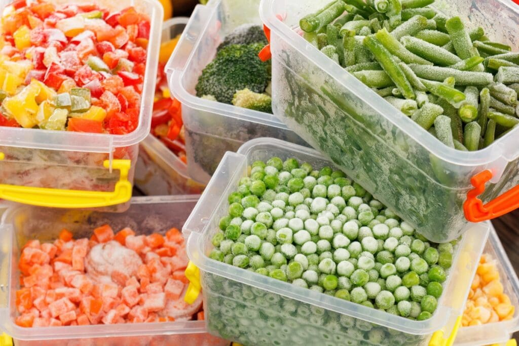 Mixed frozen vegetables in a transparent plastic food container.
