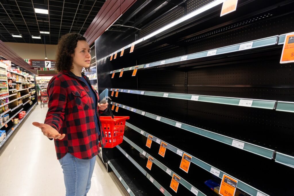 Woman looking at empty store shelf where sale item is sold out.