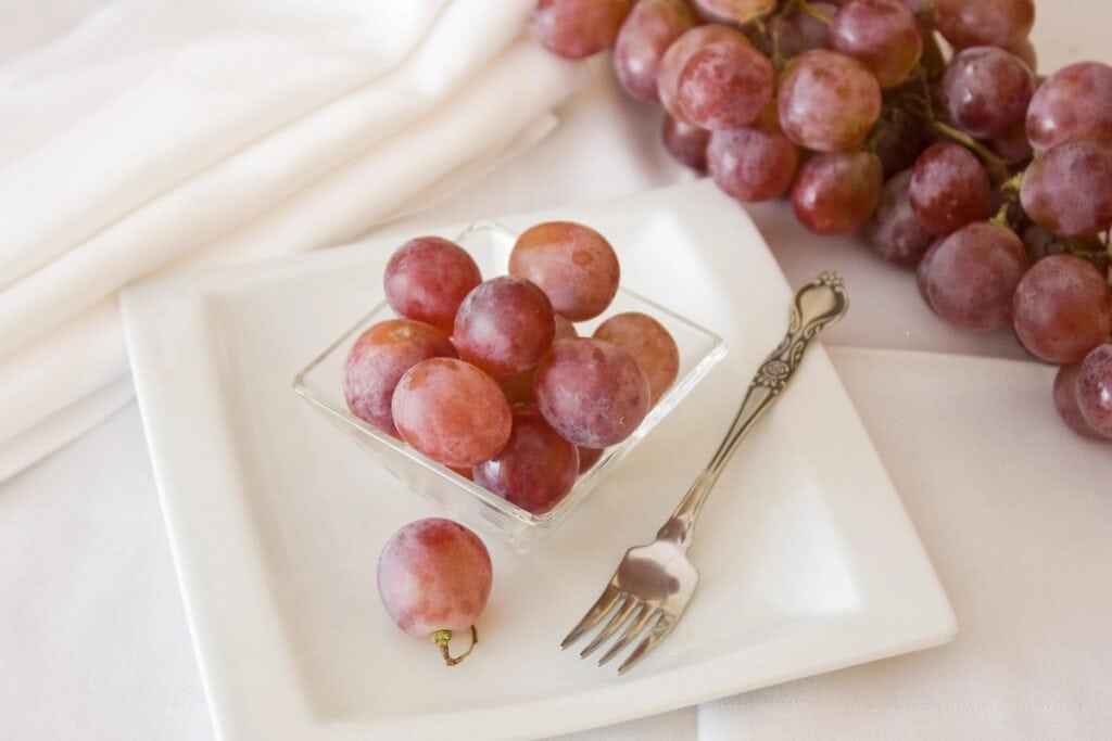 Grapes on white plate with fork on the side.