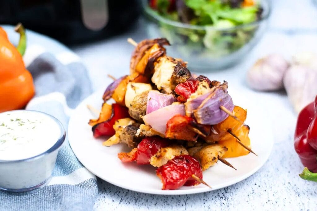 Grilled Greek chicken skewers served on a white plate.