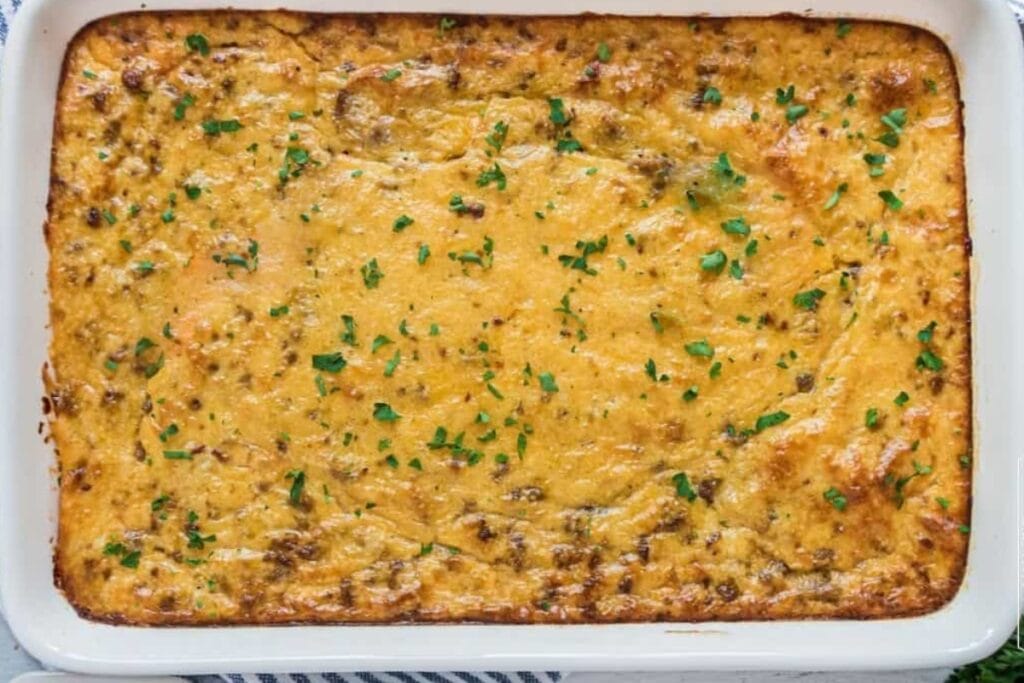 Grits and sausage casserole in a white baking dish.