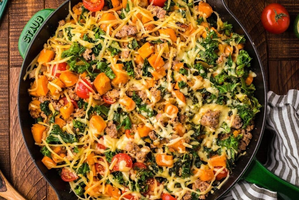 Ground turkey with sweet potato and kale cooked in a black skillet.