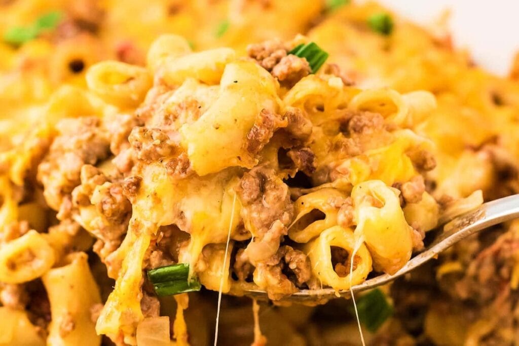 Close-up of cheesy hamburger casserole being scooped with a spoon.