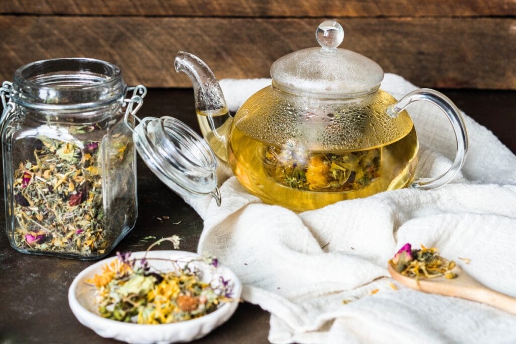 Herbal tea with teapot and dried herbs.