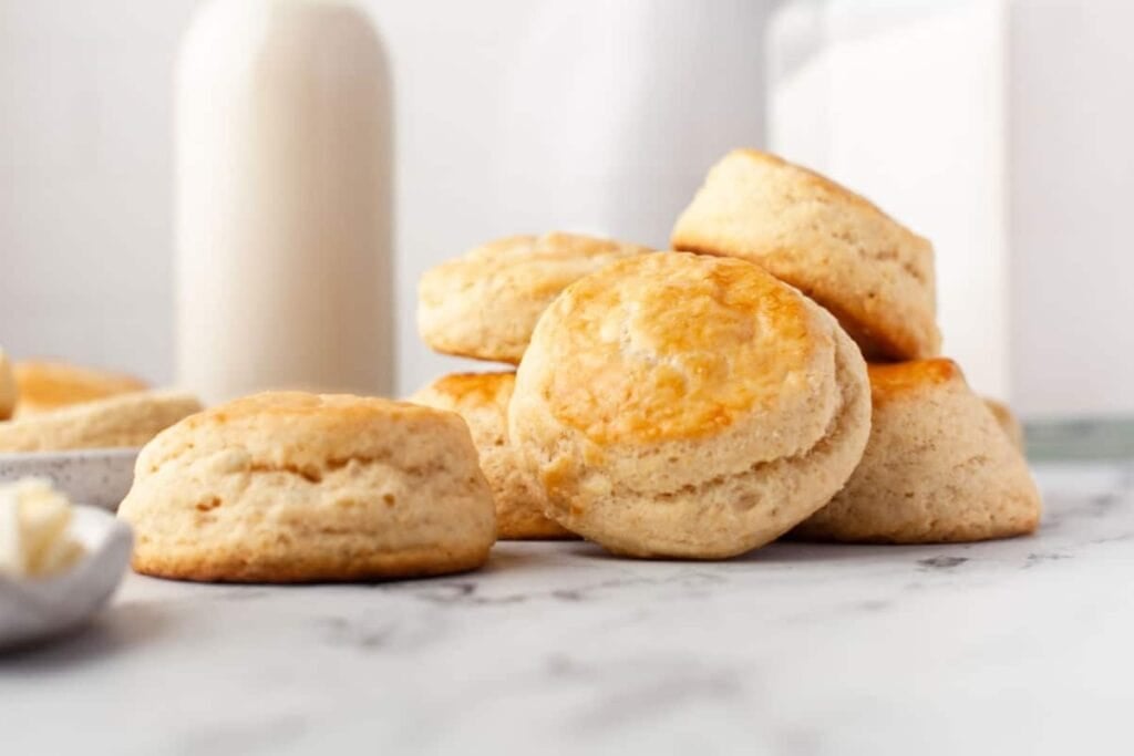 Homemade buttermilk biscuits on a marble table with a bottle of milk.