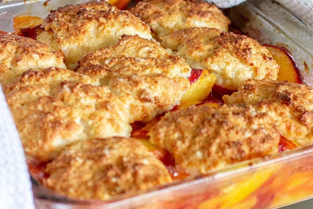 Homemade peach cobbler in a glass baking dish.